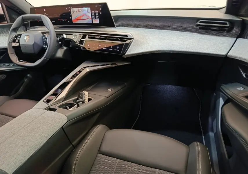 Intérieur avant droit du Peugeot 3008 blanc 2025, tableau de bord moderne avec écran tactile large et volant cuir multifonctions.