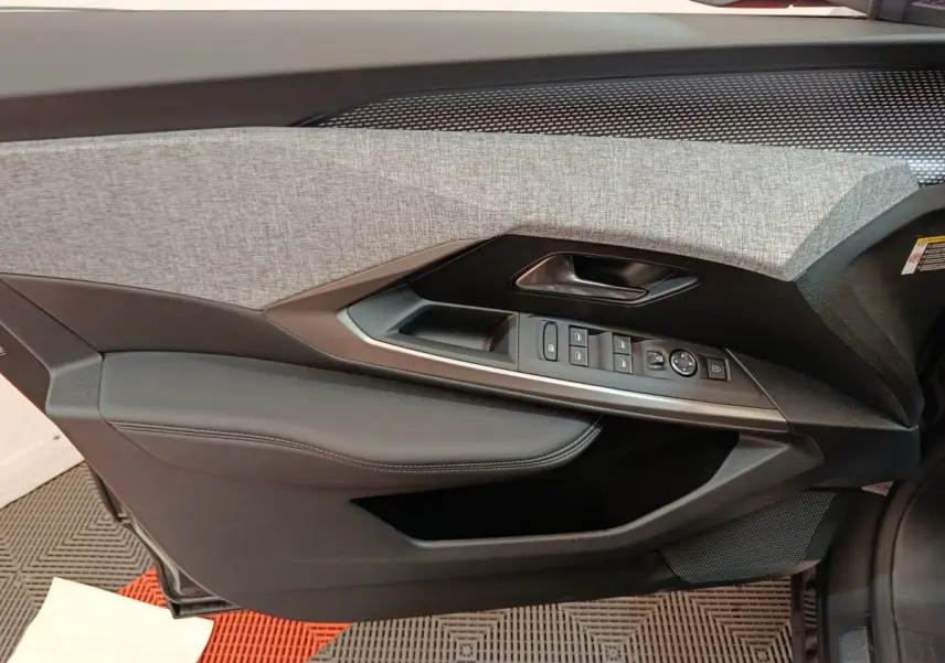 Vue intérieure côté gauche de la porte d'un Peugeot 3008 blanc 2025, avec garniture grise et commandes électriques.