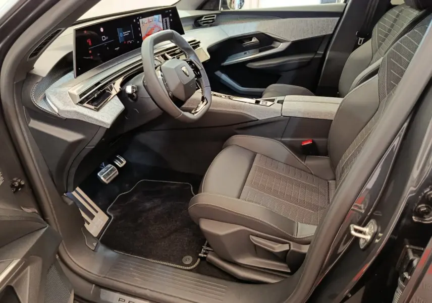 Intérieur côté conducteur du Peugeot 3008 blanc 2025, avec tableau de bord numérique panoramique et sièges en tissu gris.