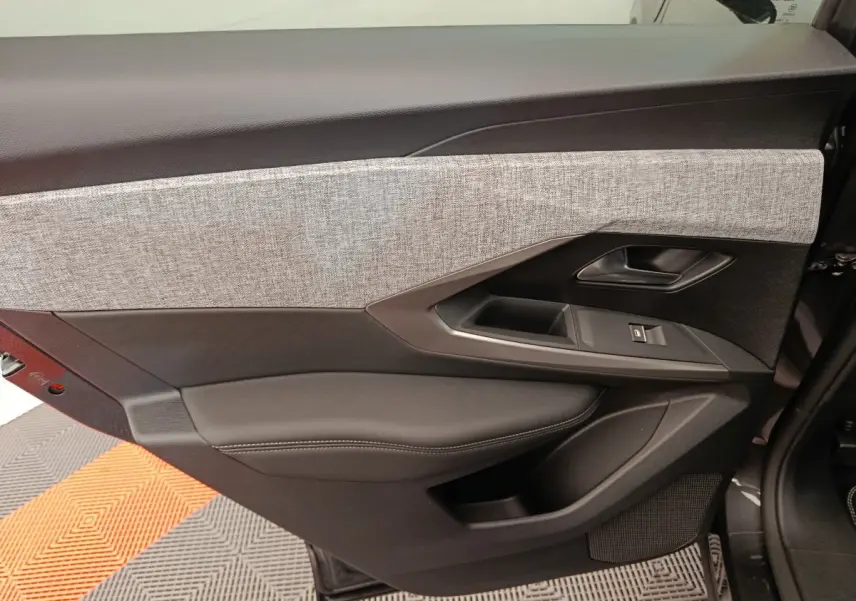 Panneau intérieur côté gauche de la porte avant d'un Peugeot 3008 blanc, avec revêtement tissu gris et commandes de fenêtre.