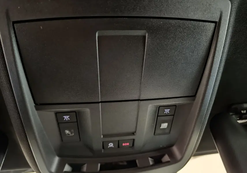 Vue intérieure du plafond de la Peugeot 3008 GT blanc 2025, avec commandes d'éclairage et bouton SOS éclairé rouge.