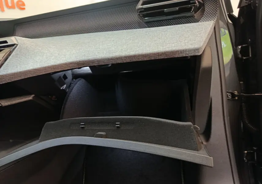 Intérieur du Peugeot 3008 1.2 Hybrid GT 2025 montrant la boîte à gants ouverte avec habillage gris clair et noir.