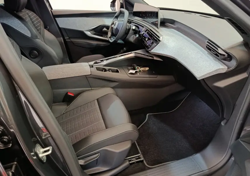 Vue intérieure côté conducteur du Peugeot 3008 1.2 Hybrid 145 GT 2025, tableau de bord moderne avec écran tactile et sièges noirs.