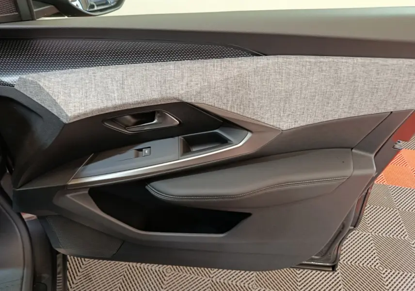 Gros plan sur la garniture intérieure côté gauche de porte du Peugeot 3008 blanc, avec tissu gris et cuir noir.