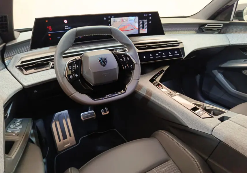 Vue intérieure du poste de conduite du Peugeot 3008 hybride 2025 avec volant compact et double écran tactile.