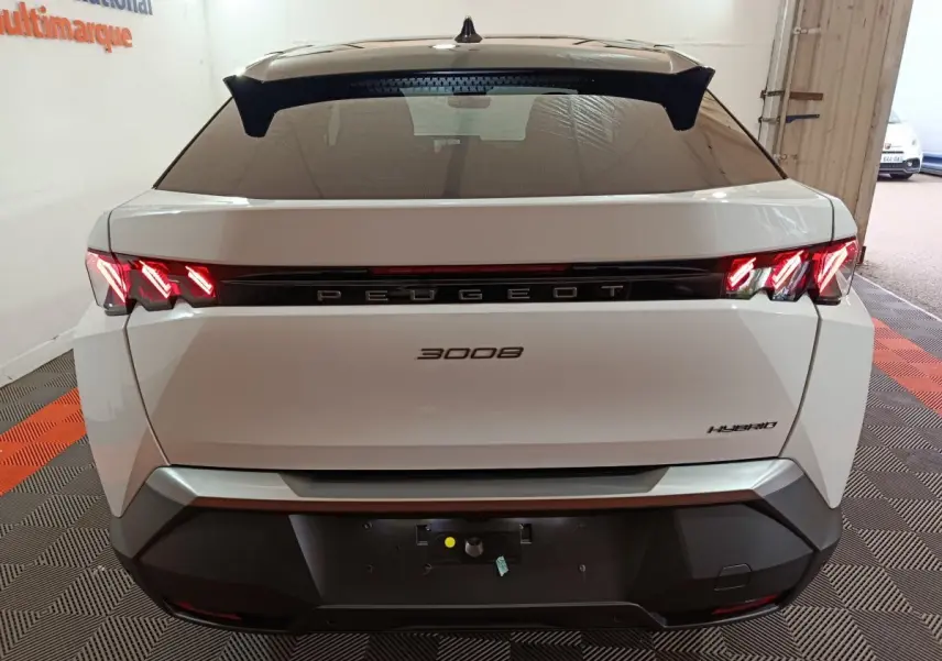 Vue arrière d'un Peugeot 3008 blanc hybride 2025 avec feux LED allumés et logo central noir brillant.