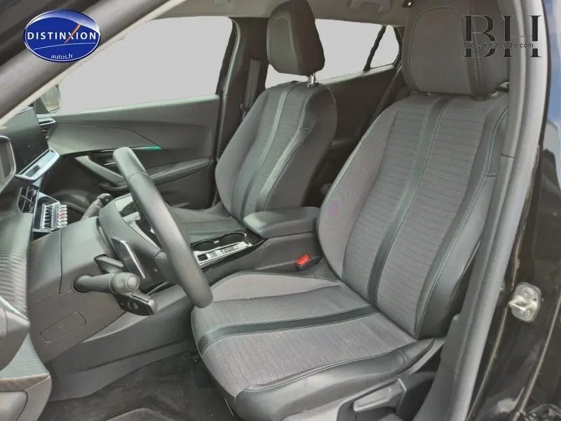 Vue intérieure côté conducteur du Peugeot 2008 2021, sièges tissu tri-matières gris avec inserts noirs, volant multifonction visible.