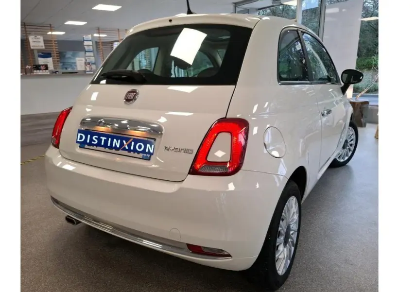 Vue 3/4 arrière droite d'une Fiat 500 blanche Bossa Nova avec badge Hybrid, en intérieur showroom.