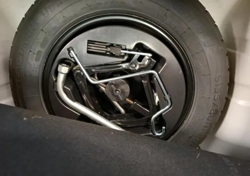 Gros plan sur la roue de secours et les outils de bord dans le coffre d'une Fiat 500 blanche Bossa Nova 2022.