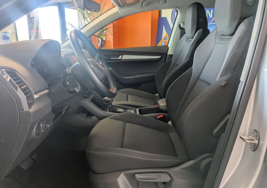 Vue intérieure côté conducteur du Skoda Karoq gris argent 2023, sièges tissu noirs et tableau de bord moderne.