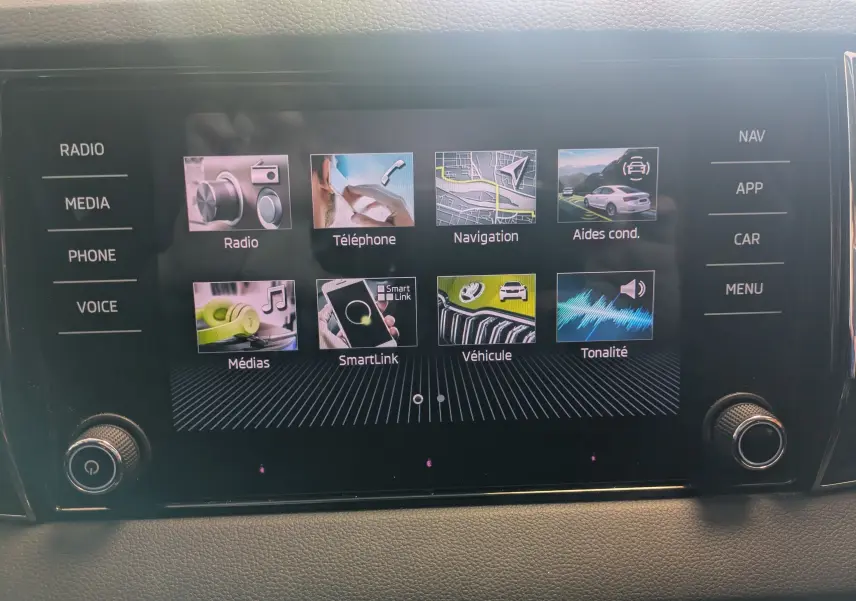 Écran tactile central du Skoda Karoq 2023 affichant les menus radio, téléphone, navigation et aides à la conduite.