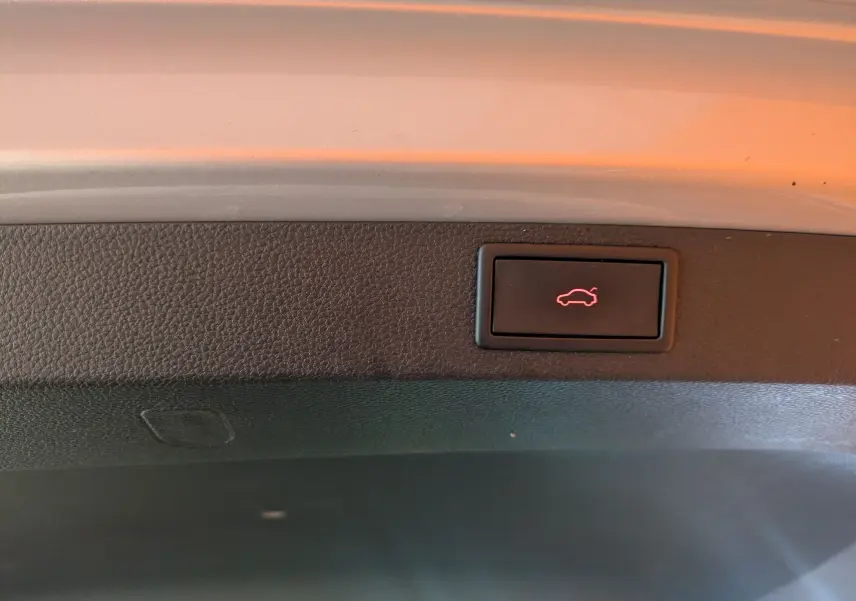 Bouton d'ouverture électrique du hayon visible sur le bord intérieur du coffre du Skoda Karoq gris argent 2023.