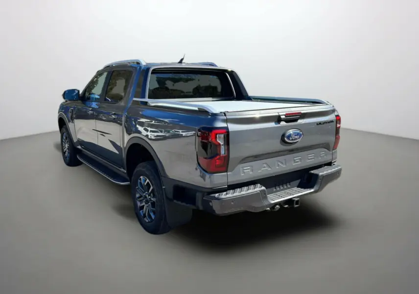 Ford Ranger gris carbone en 3/4 arrière droit, avec benne couverte et jantes alu 18 pouces visibles.