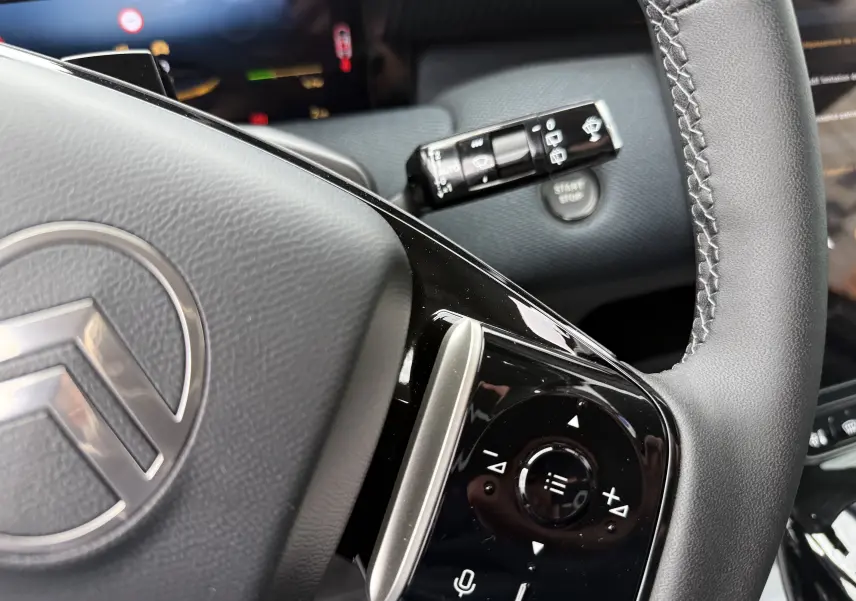 Gros plan sur le volant du Citroën C5 Aircross II Hybrid 2026 avec commandes intégrées et bouton start/stop visible en arrière-plan.