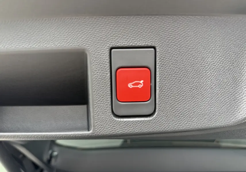 Bouton rouge d'ouverture électrique du hayon sur le panneau intérieur du coffre d'un Citroën C5 Aircross II Hybrid 2026.