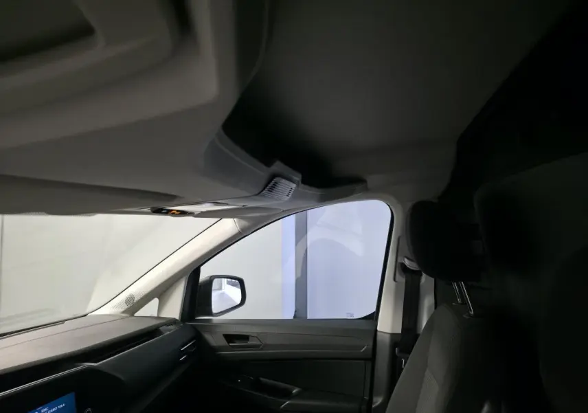 Vue intérieure côté passager avant du Volkswagen Caddy Cargo gris, mettant en valeur le siège et la portière.