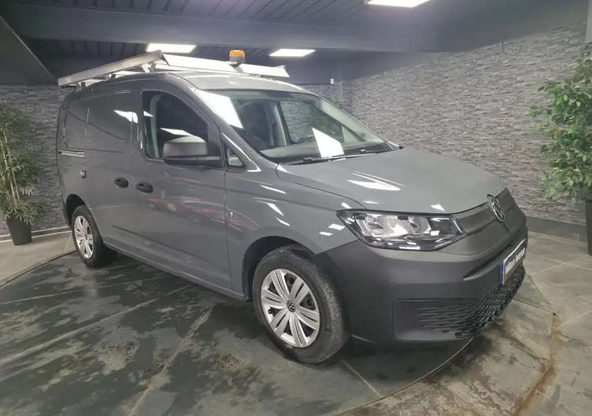 Volkswagen Caddy Cargo gris en 3/4 avant droit avec galerie de toit et jantes acier noires.