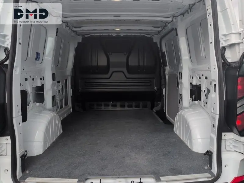 Vue intérieure arrière du fourgon Ford Transit Custom blanc Glacier, montrant l'espace de chargement vide et la cloison noire.