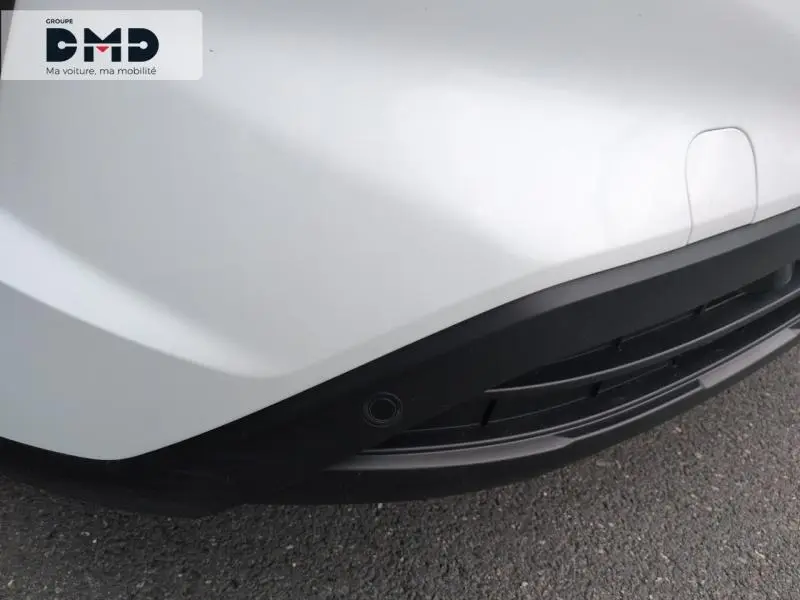 Gros plan sur le pare-chocs avant blanc glacier du Ford Transit Custom avec capteur de stationnement intégré.