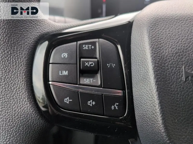 Gros plan sur les commandes multifonctions noires à gauche du volant du Ford Transit Custom blanc Glacier 2024.