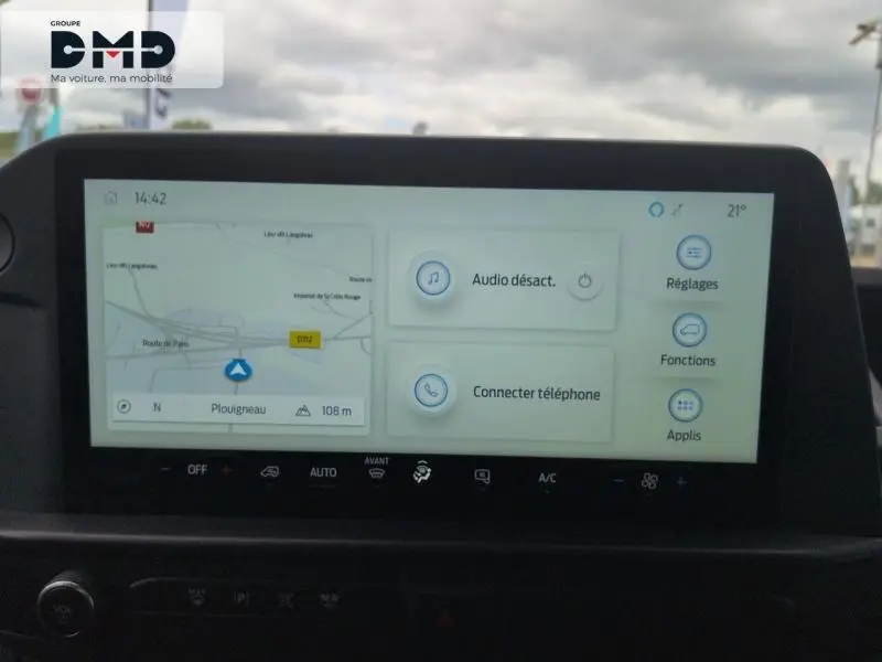 Écran tactile central du Ford Transit Custom blanc montrant la navigation et les options audio, vue intérieure frontale.