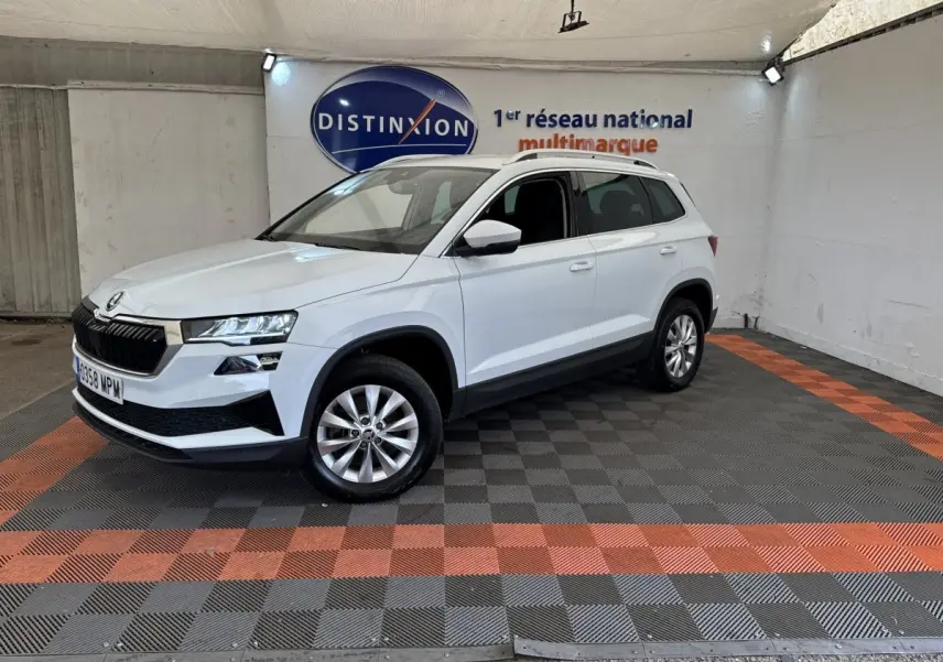 Vue 3/4 avant droite d’un Skoda Karoq blanc avec calandre noire et jantes alliage dans un showroom.