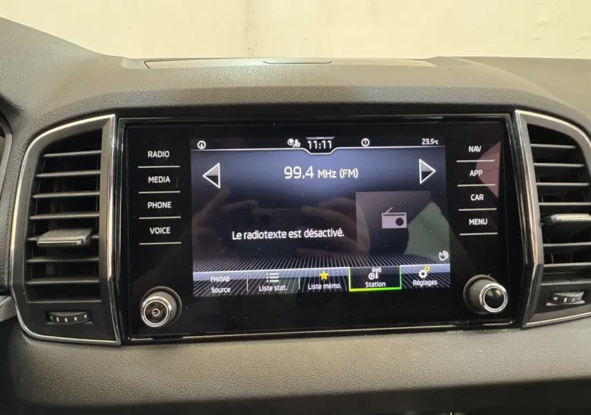 Écran tactile central du tableau de bord du Skoda Karoq blanc, affichant la radio FM à 99,4 MHz.
