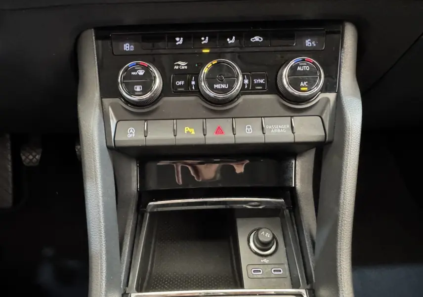 Vue rapprochée du tableau de bord central noir du Skoda Karoq 2024 avec commandes climatisation et prises USB visibles.