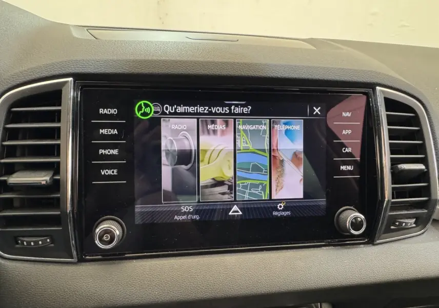 Écran tactile central du tableau de bord du Skoda Karoq blanc, affichant le menu principal multimédia et navigation.