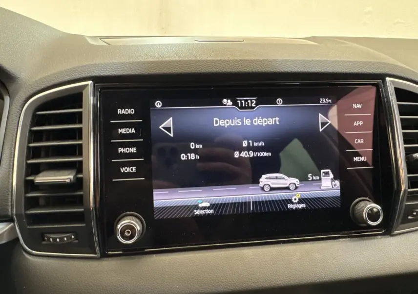 Écran tactile central du tableau de bord du Skoda Karoq blanc, affichant les données de trajet et consommation.