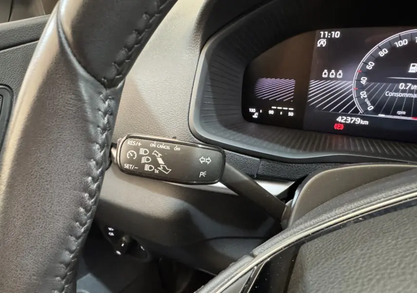 Gros plan sur le combiné d'instruments et la commande multifonction à gauche du volant cuir dans un Skoda Karoq blanc 2024.