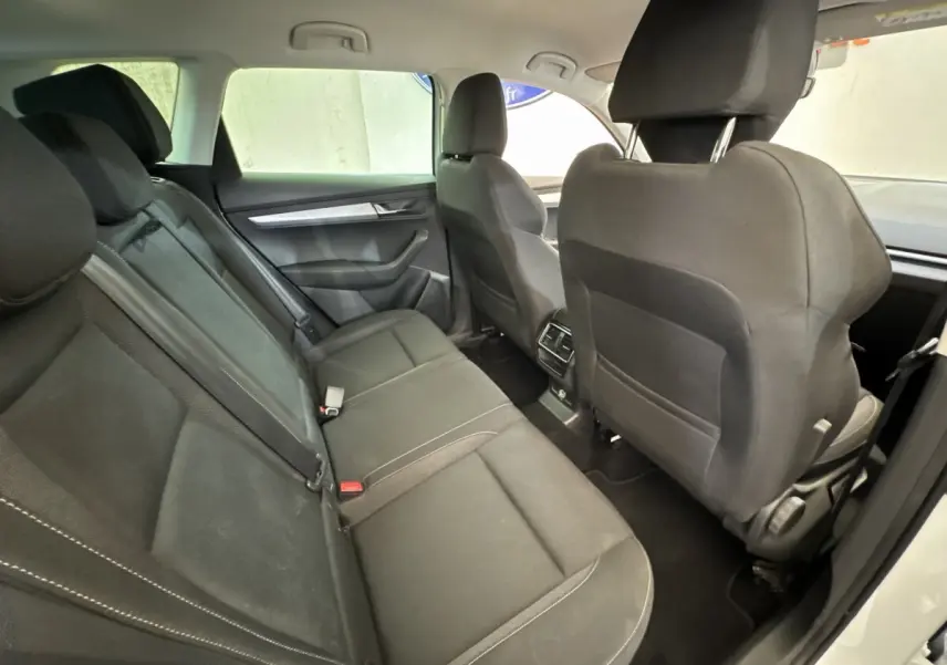 Vue intérieure arrière montrant les sièges noirs du Skoda Karoq 2024 avec accoudoirs centraux et espace passagers.