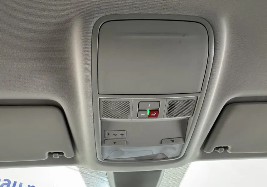 Vue intérieure du plafond avant gris clair du Skoda Karoq blanc 2024 avec commandes d'éclairage et bouton SOS éclairé.