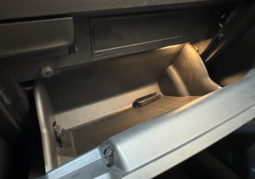 Gros plan sur la boîte à gants ouverte et éclairée à l'intérieur d'un Skoda Karoq blanc 2024.