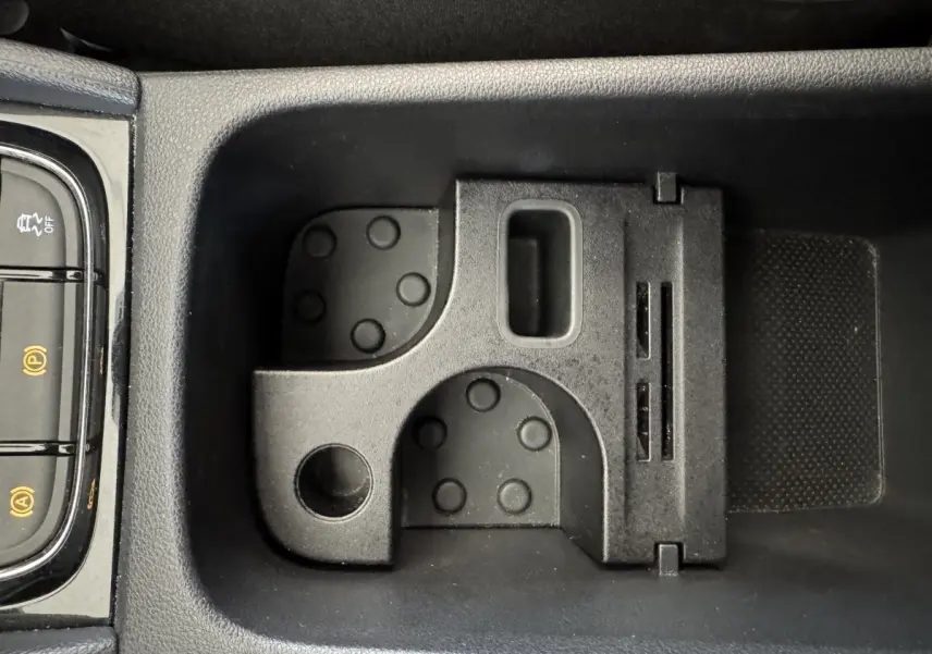 Gros plan sur le rangement central noir avec porte-cartes et commandes électroniques du Skoda Karoq blanc 2024.