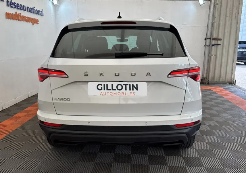 Vue arrière d'un Skoda Karoq blanc 2024 dans un garage avec feux arrière LED et logo ŠKODA visible.
