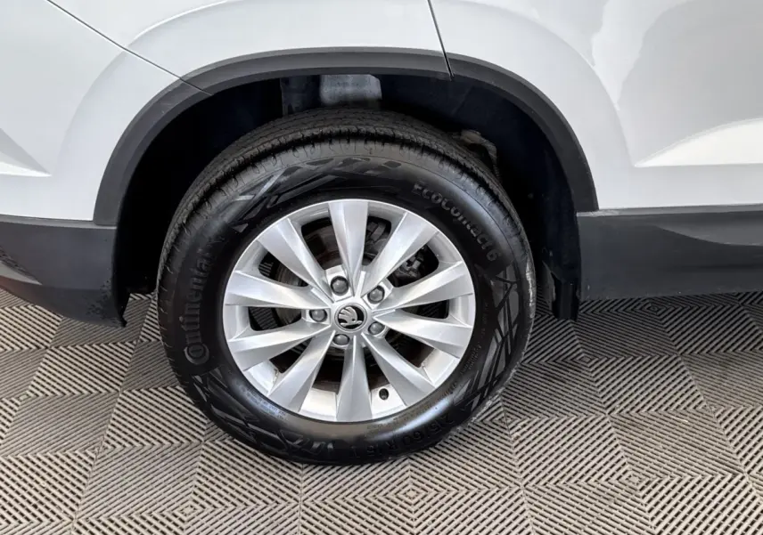 Gros plan sur la roue avant droite d’un Skoda Karoq blanc, avec jante argentée et pneu Continental.