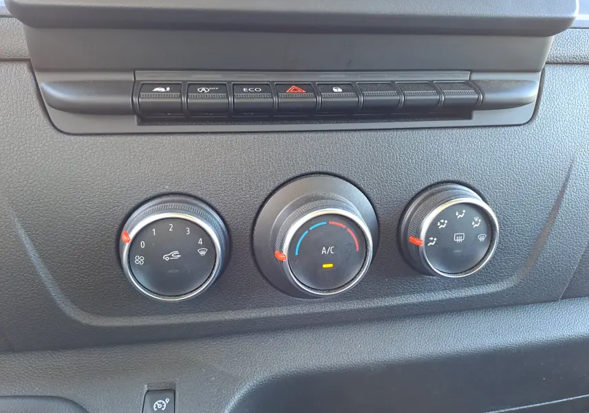 Gros plan sur les commandes de climatisation et boutons de fonction du tableau de bord noir du Nissan Interstar Chassis Cabine blanc 2024.