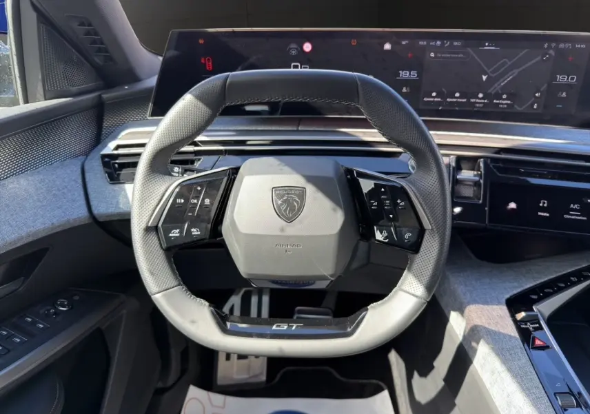 Vue rapprochée du volant cuir GT et du tableau de bord numérique du Peugeot 5008 gris foncé hybride 2025.