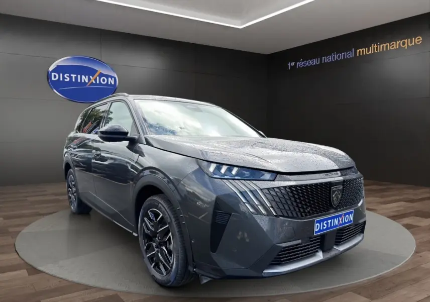 Peugeot 5008 gris foncé vue 3/4 avant, avec calandre noire distinctive et jantes alliage noires.