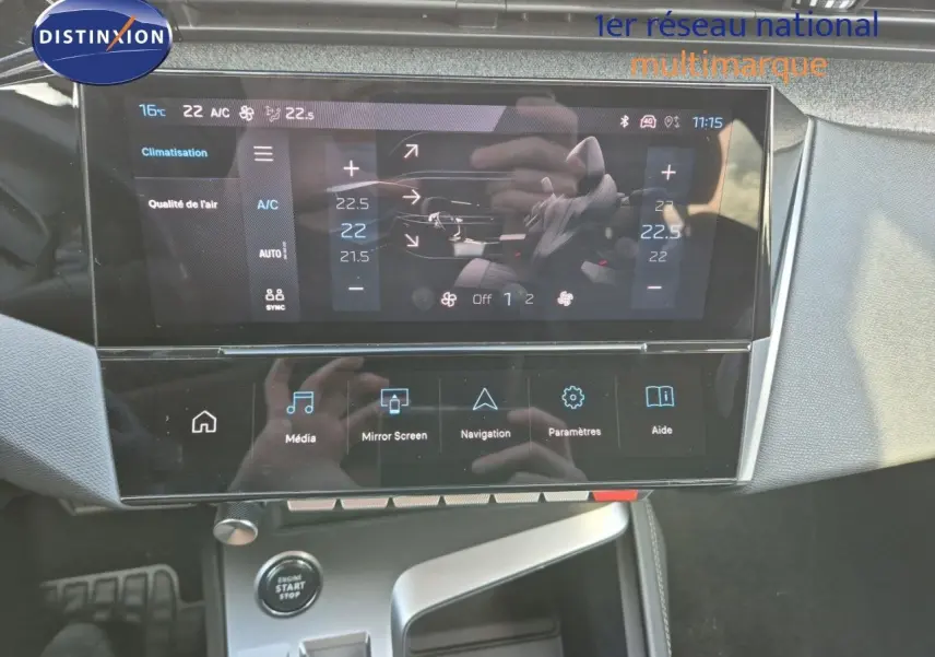 Vue rapprochée de la console centrale tactile de la Peugeot 308 2023 en Vert Olivine, affichant la climatisation et les options multimédia.
