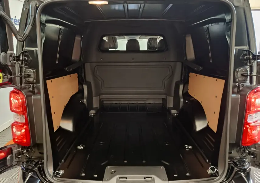 Vue arrière du coffre noir du Citroën Jumpy XL 2025, montrant l'espace de chargement avec cloisons latérales en bois.