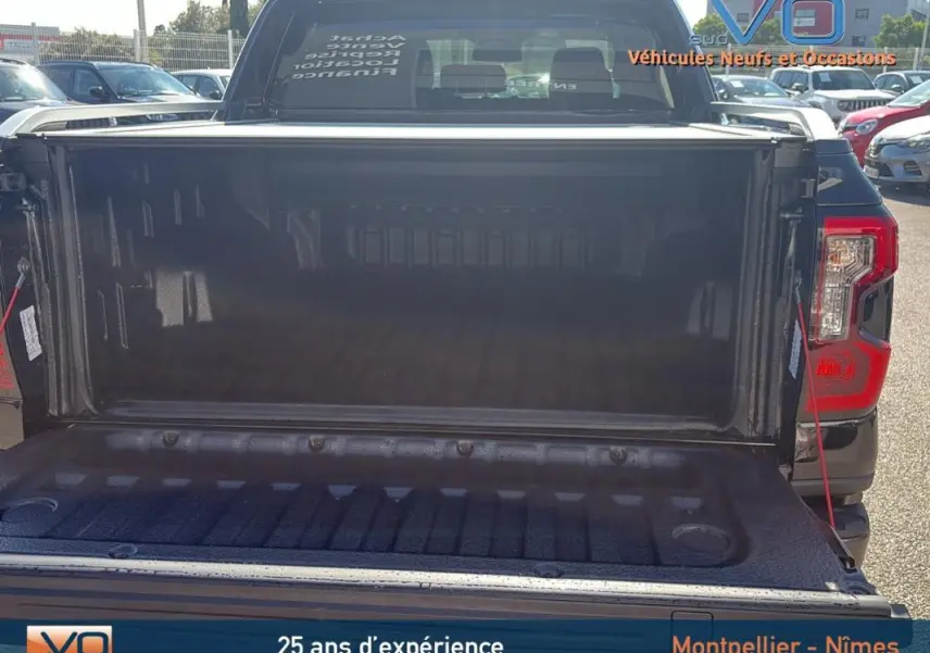 Vue arrière du Ford Ranger noir 2025 avec benne ouverte, mettant en valeur l’espace de chargement vide et les feux arrière.