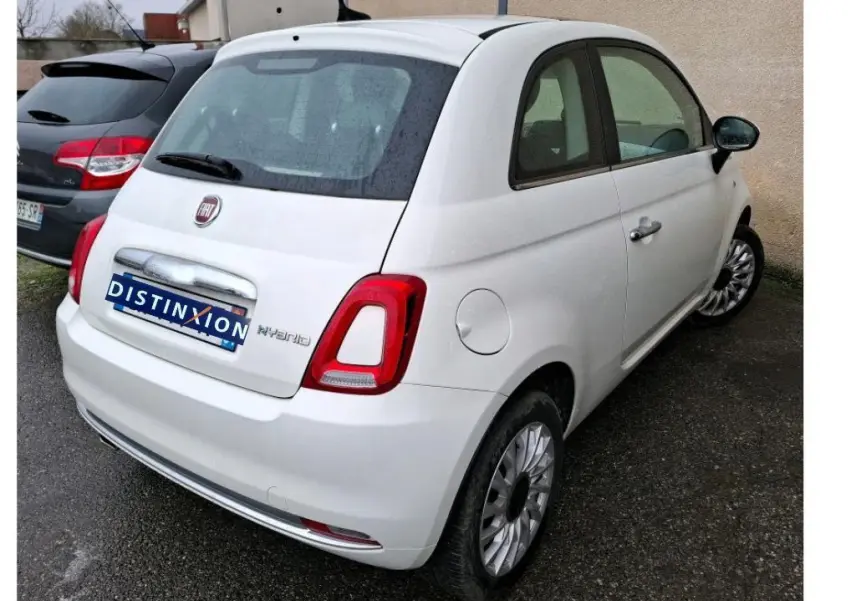 Vue 3/4 arrière droite d'une Fiat 500 blanche Bossa Nova avec logo Hybrid visible sur un parking.