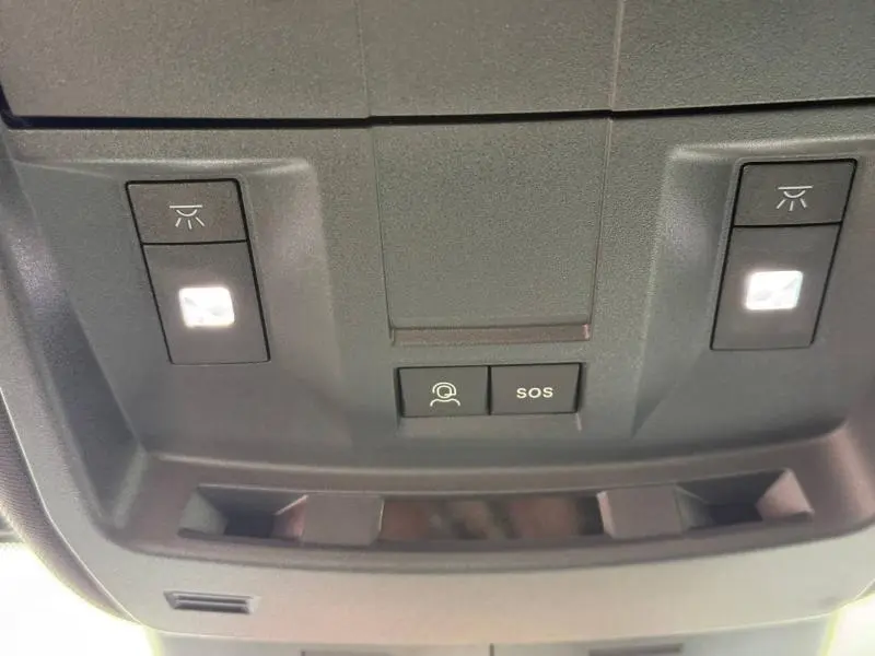Gros plan sur les commandes d’éclairage et bouton SOS du plafonnier intérieur du Peugeot 5008 Hybrid blanc Okénite.