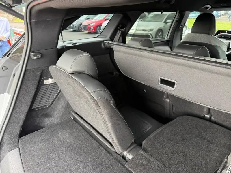 Vue intérieure arrière du Peugeot 5008 Hybrid blanc Okénite, montrant la banquette partiellement rabattue et la plage arrière.
