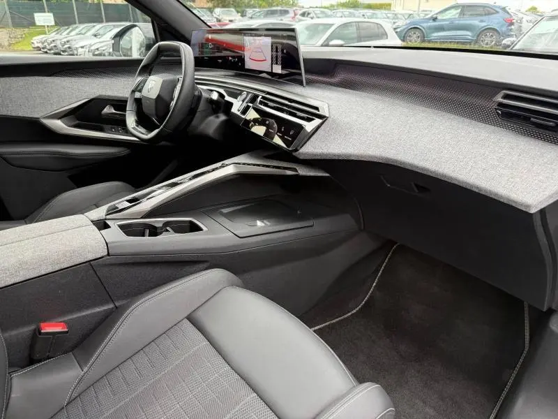 Vue intérieure côté passager du Peugeot 5008 Hybrid 145ch GT 2025, mettant en valeur le tableau de bord moderne et les finitions tissu et cuir.