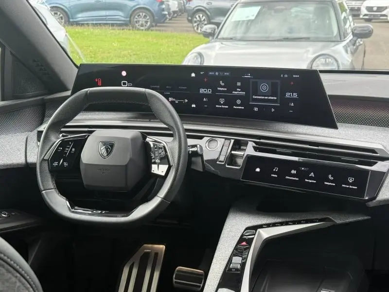 Vue intérieure du tableau de bord et volant du Peugeot 5008 Hybrid 145ch GT, avec écrans numériques larges et design moderne.