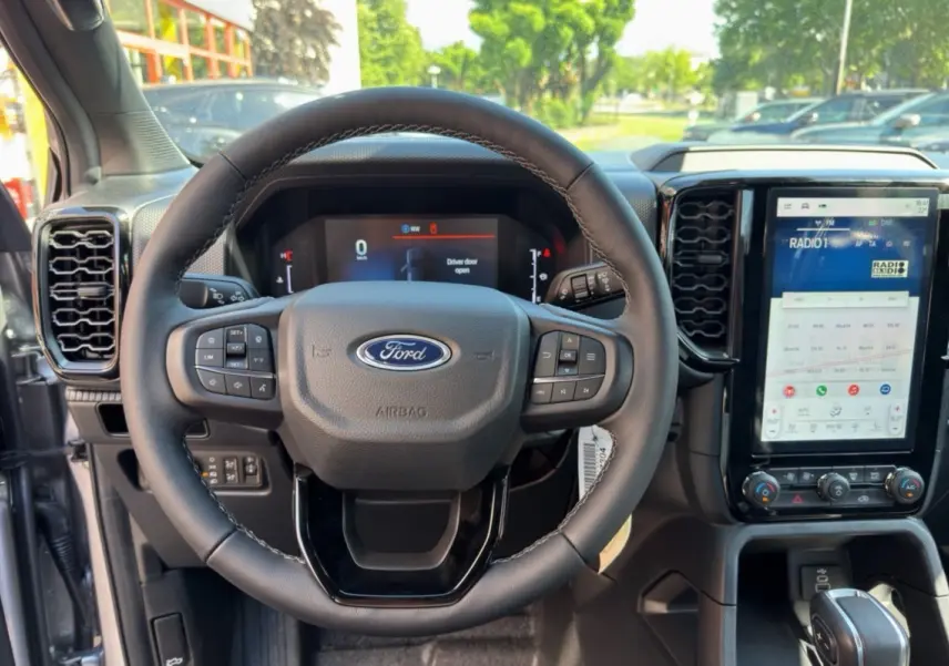 Vue intérieure centrée sur le volant cuir multifonctions et l'écran tactile vertical du Ford Ranger gris iconic 2026.