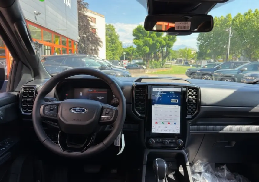 Vue intérieure frontale du Ford Ranger gris iconic, avec volant cuir multifonctions et grand écran tactile vertical central.